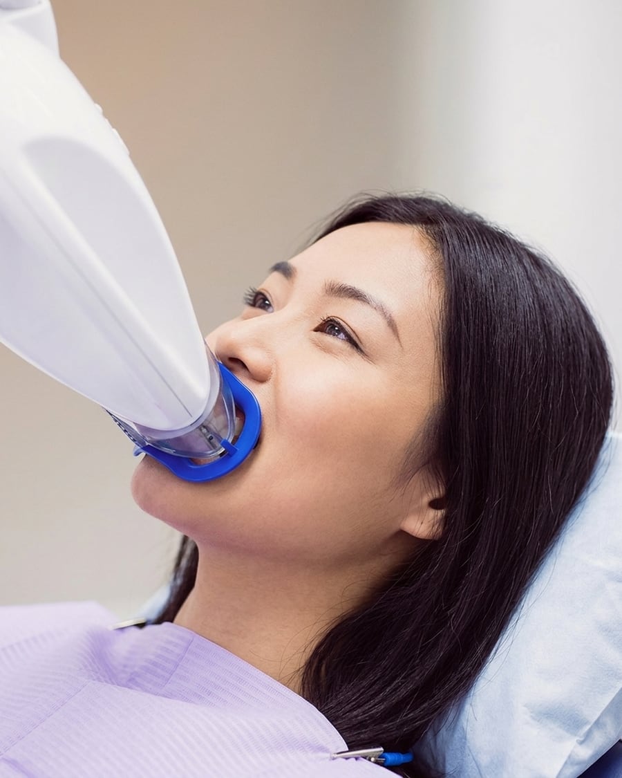 Patient having in-clinic teeth whitening with a blue LED whitening light at Dr Ray & Partners Dental